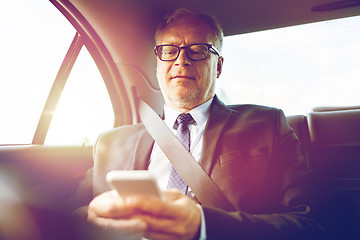 Image showing senior businessman texting on smartphone in car