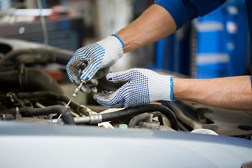 Image showing mechanic with dipstick checking motor oil level