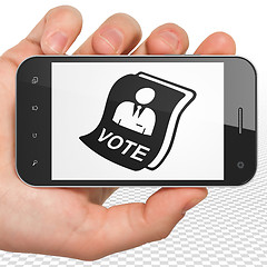 Image showing Politics concept: Hand Holding Smartphone with Ballot on display