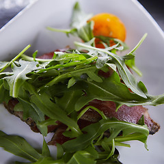 Image showing slice of prosciutto or jamon with arugula leafs