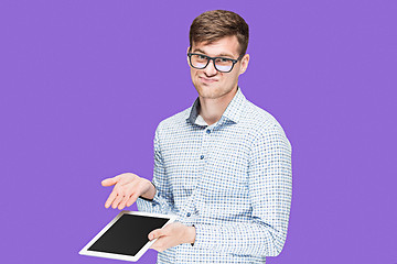 Image showing The young man in a shirt working on laptop on lilac backgroundin