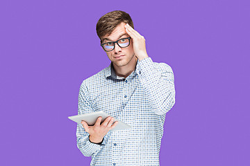 Image showing The young man in a shirt working on laptop on lilac backgroundin