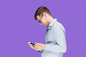 Image showing The young man in a shirt working on laptop on lilac backgroundin