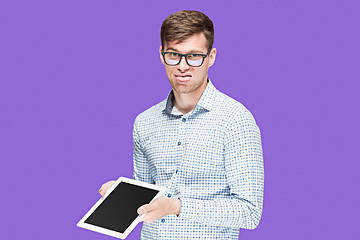 Image showing The young man in a shirt working on laptop on lilac backgroundin