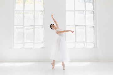 Image showing Young and incredibly beautiful ballerina is posing and dancing in a white studio