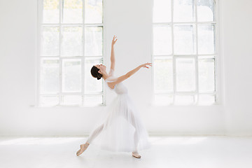 Image showing Young and incredibly beautiful ballerina is posing and dancing in a white studio