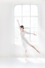 Image showing Young and incredibly beautiful ballerina is posing and dancing in a white studio