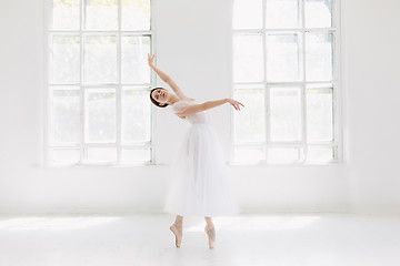 Image showing Young and incredibly beautiful ballerina is posing and dancing in a white studio