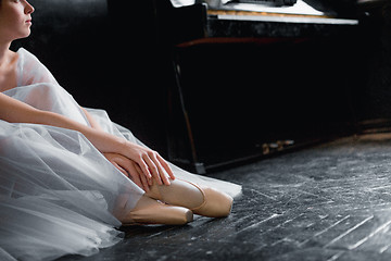 Image showing Young ballerina dancing, closeup on legs and shoes, sitting in pointe shooses