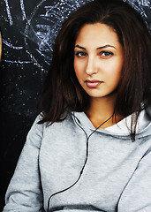 Image showing young cute teenage girl in classroom at blackboard seating on ta