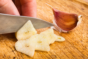 Image showing hand slicing garlic cloves