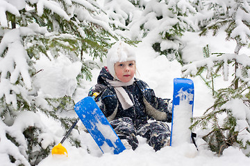 Image showing little girl in skiing sits on the snow