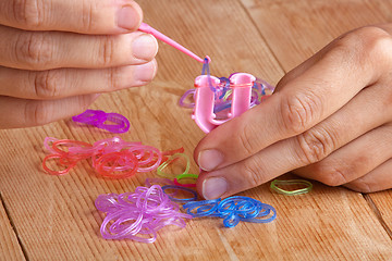 Image showing hands making rubber band bracelet, closeup