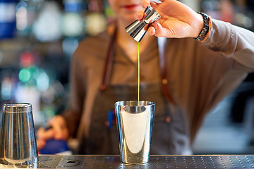 Image showing bartender with cocktail shaker and jigger at bar