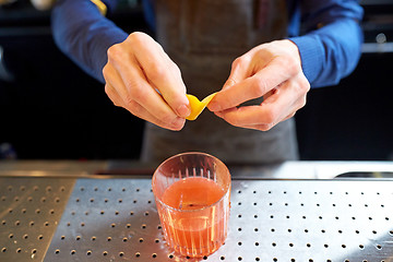 Image showing bartender with glass of cocktail and lemon peel