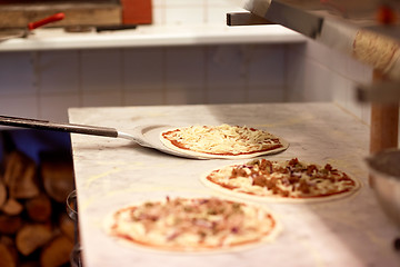 Image showing peel taking pizza off table at pizzeria