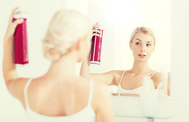 Image showing woman with hairspray styling her hair at bathroom