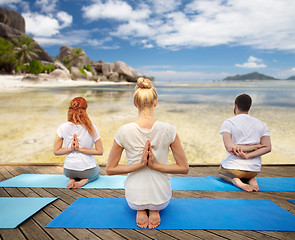 Image showing group of people making yoga exercises over beach