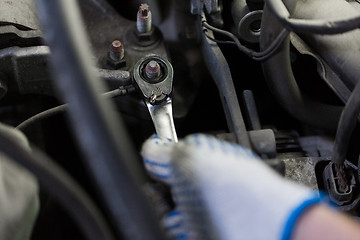 Image showing mechanic man with wrench repairing car at workshop