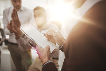 Image showing business team and man writing to notepad at office