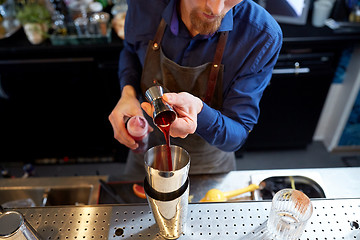 Image showing bartender with shaker preparing cocktail at bar