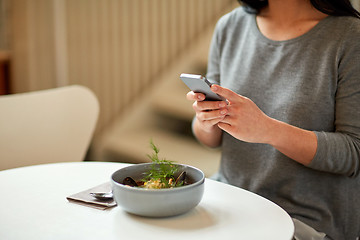 Image showing woman with smartphone and bowl of soup at cafe