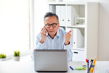 Image showing businessman with laptop calling on smartphone