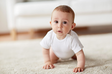 Image showing little baby in diaper crawling on floor at home