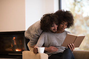 Image showing multiethnic couple hugging in front of fireplace