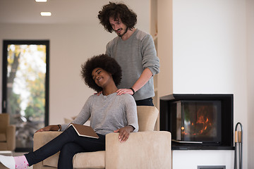 Image showing multiethnic couple hugging in front of fireplace