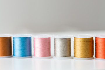 Image showing row of colorful thread spools on table