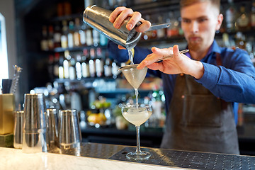 Image showing bartender with shaker preparing cocktail at bar