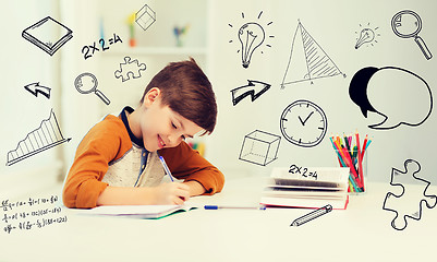 Image showing smiling student boy writing to notebook at home