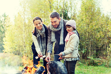 Image showing happy family roasting marshmallow over campfire