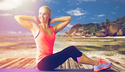 Image showing smiling woman exercising on mat outdoors