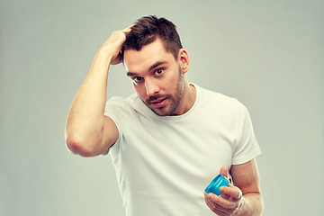 Image showing happy young man styling his hair with wax or gel