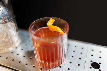 Image showing glass with cocktail and orange peel at bar counter