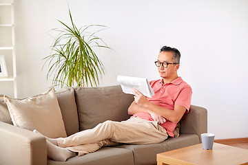 Image showing happy man in glasses reading newspaper at home