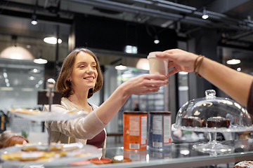 Image showing happy woman taking coffee cup from seller at cafe