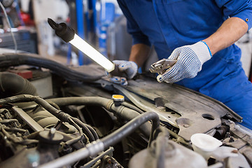 Image showing mechanic man with pliers repairing car at workshop