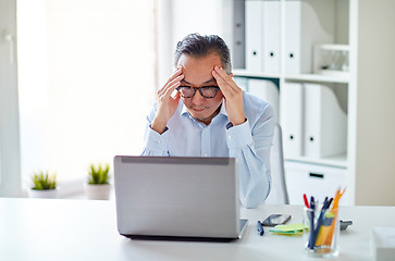 Image showing businessman in eyeglasses with laptop at office