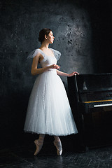 Image showing Young and incredibly beautiful ballerina is posing in a black studio