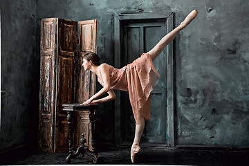 Image showing Young and incredibly beautiful ballerina is posing and dancing in a black studio