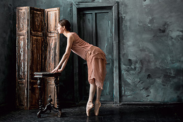 Image showing Young and incredibly beautiful ballerina is posing and dancing in a black studio