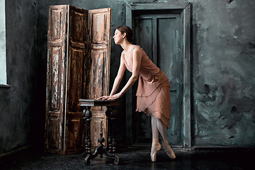 Image showing Young and incredibly beautiful ballerina is posing and dancing in a black studio