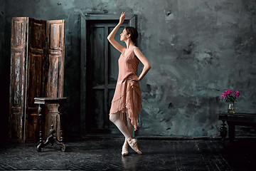 Image showing Young and incredibly beautiful ballerina is posing and dancing in a black studio