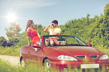 Image showing happy friends with camera driving in cabriolet car