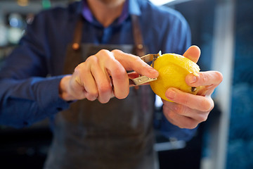 Image showing bartender removing peel from lime at bar