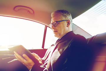 Image showing senior businessman with tablet pc driving in car