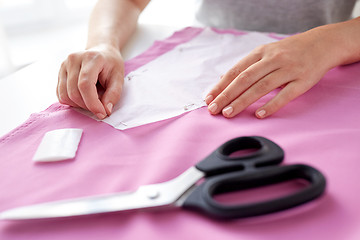 Image showing woman with pins stitching paper pattern to fabric